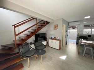 a living room with a staircase and some chairs at Beautiful Casa em Riviera in Bertioga