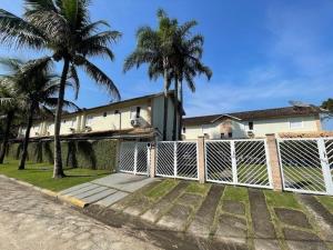 a fence in front of a house with palm trees at Beautiful Casa em Riviera in Bertioga