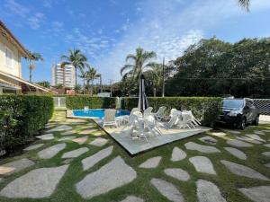 a yard with a pool and chairs and a car at Beautiful Casa em Riviera in Bertioga