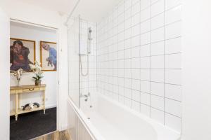 a bathroom with white tile walls and a tub at Printworks Building City Centre Penthouse 5 Bedrooms Sleeps 14 in Gloucester