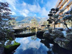 a pond in front of a building with mountains in the background at Bosenkan in Gero