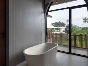 a white bath tub in a bathroom with a window at 4Bedroom Umah Jeng Alessia Villa - Pererenan by SooBali in Munggu +16 photos