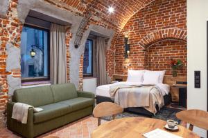 a bedroom with a bed and a couch and a brick wall at Nomadic Urban Premium Suites in Krakow +110 photos