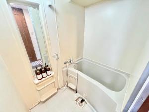 een witte badkamer met een bad en een raam bij 大国町駅徒歩3分 なんば駅1駅 最大4名 ロイヤル507 in Osaka +19 foto's
