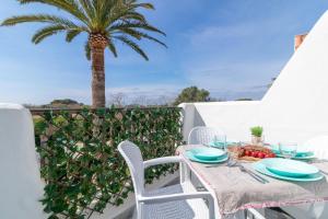 a table and chairs on a balcony with a palm tree at Ca'n Pekos Apartamento en la playa de Son Bou in Son Bou