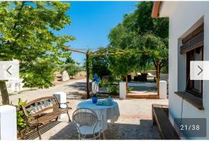 a patio with a table and chairs and trees at Cortijo Rica in Seco de Lucena