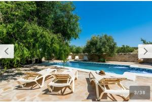 a resort with a swimming pool with chairs and a swimming pool at Cortijo Rica in Seco de Lucena