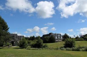 una fila de casas en un campo verde con un cielo azul en Strand 104, en Hollum