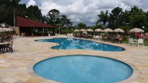 a swimming pool with tables and chairs and a restaurant at Hotel Nascentes da Serra in Poços de Caldas