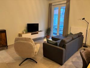 a living room with a couch and a chair and a television at Ruytingen Modern Seaside Suite in Koksijde