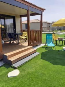 a deck with a table and chairs on the grass at Charmant Cottage in Saubrigues +1 photo