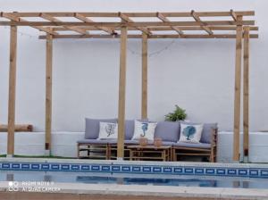 a pergola over a swimming pool with purple furniture at Casa El Veranito in Chiclana de la Frontera