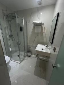 a white bathroom with a shower and a sink at Hostal Plaza in Marmolejo