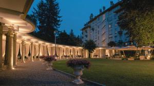 a lit up building with vases with flowers in a park at Palace Grand Hotel Varese in Varese