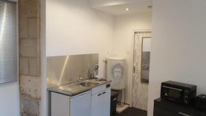 a small kitchen with a sink and a microwave at Studio 2 - 3 minutes du Futuroscope in Chasseneuil-du-Poitou +2 photos