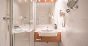 a white bathroom with a sink and a shower at PLAZA INN Goslar in Goslar