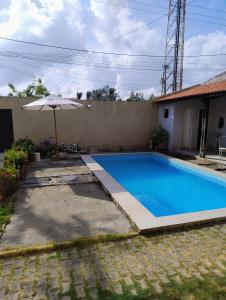 ein Swimmingpool mit Sonnenschirm neben einem Haus in der Unterkunft Flat do Rafa in Caucaia
