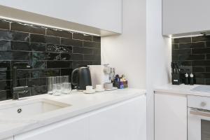 une cuisine avec un évier et un mur carrelé noir dans l'établissement Golden Apartments Warsaw - Luxury 2-Bedroom, Mennica Residence&166, à Varsovie 25 autres photos