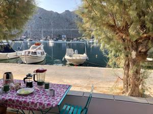 une table et des chaises avec des bateaux dans l'eau dans l'établissement La DESIRADE, à Symi