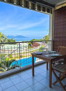 ein Balkon mit Tisch und Blick auf das Meer in der Unterkunft Manui Condo avec piscine et vue sur la mer et l'île de Moorea in Punaauia