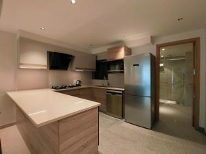 a kitchen with a stainless steel refrigerator and wooden cabinets at Luxury Suites by Eden Wellness and Hospitality in Dehradun +61 photos