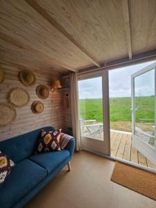 a living room with a blue couch and a sliding glass door at Surf Shack in Scharendijke