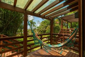 - un hamac sur une terrasse avec des arbres en arrière-plan dans l'établissement Coração da Terra Praia do Rosa, à Praia do Rosa