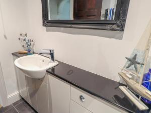 a bathroom with a sink and a mirror on the wall at The Studio Cottage in Cemaes Bay