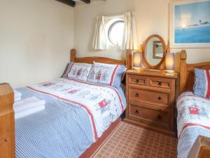 a bedroom with a bed and a dresser with a mirror at The Studio Cottage in Cemaes Bay +6 photos