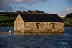 a stone building in the middle of a body of water at Hostal-Restaurante Casa Giz in Cuiña