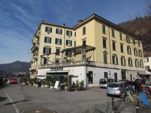 un gran edificio con coches estacionados frente a él en Al Porticciolo di Sant'Agostino, en Como