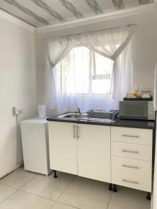 una cucina bianca con lavandino e finestra di Cozy corner a East London