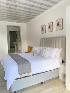 una camera da letto con un letto grande con lenzuola e cuscini bianchi di Cozy corner a East London Altre 7 foto