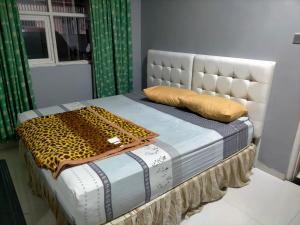 a bed with a white headboard and a pillow on it at Kouzui Homestay in Surabaya