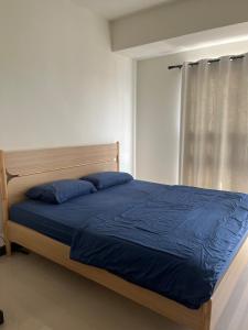 Un dormitorio con una cama con sábanas azules y una ventana. en Our Home, en Jodoh