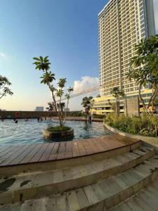 a wooden walkway with a palm tree and a building at Our Home in Jodoh