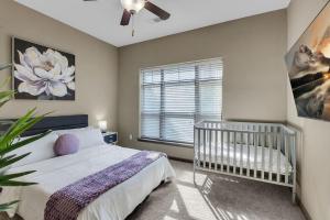 a bedroom with a crib and a large window at Chic 2BR- Pool,Gym,Pkng,Near BOK Ctr&Arts Dstrct in Tulsa +62 photos