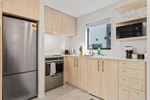 a kitchen with wooden cabinets and a stainless steel refrigerator at Auckland Peninsula Stunner in Auckland