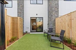 a patio with a table and chairs and a fence at Auckland Peninsula Stunner in Auckland