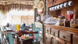 a kitchen with a table and chairs with food on it at Pescador - Pousada de Charme in Jericoacoara
