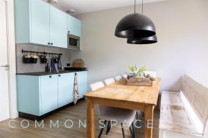 a kitchen with a wooden table and a black light fixture at Bed and Breakfast t Klijnhuysje in Kaatsheuvel