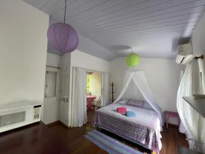 a bedroom with a bed with a canopy at Casinha da Fabi - Suítes in Pipa