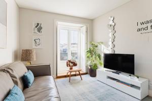 a living room with a couch and a flat screen tv at Chiado Square Apartments | Lisbon Best Apartments in Lisbon