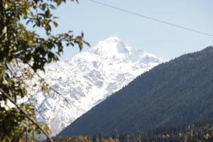 a snow covered mountain with trees in front of it at Cottage Deera in Mestia +6 photos