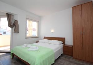 a bedroom with two beds and a window at Apartments & Rooms Dekanic in Baška