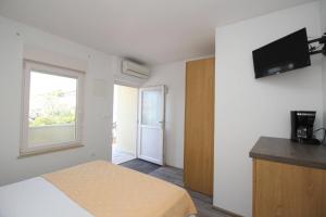 a bedroom with a bed and a television on a wall at Apartments & Rooms Dekanic in Baška