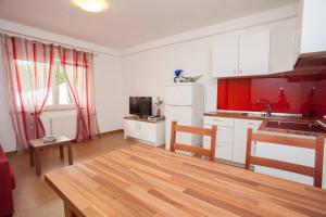 a kitchen with red walls and white cabinets and a table at Apartments & Rooms Dekanic in Baška