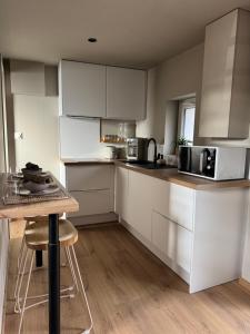 a kitchen with white cabinets and a table with stools at L ' Arbre de Guise in Seclin