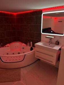ein Badezimmer mit Badewanne, Waschbecken und Spiegel in der Unterkunft Love room in Camaret-sur-Aigues