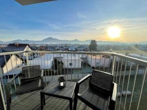 Dos sillas y una mesa en un balcón con la puesta de sol. en Urban CARTA II apartment, en Liptovský Mikuláš